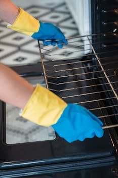 Person wearing gloves cleaning an oven, focusing on hygiene and household chores.