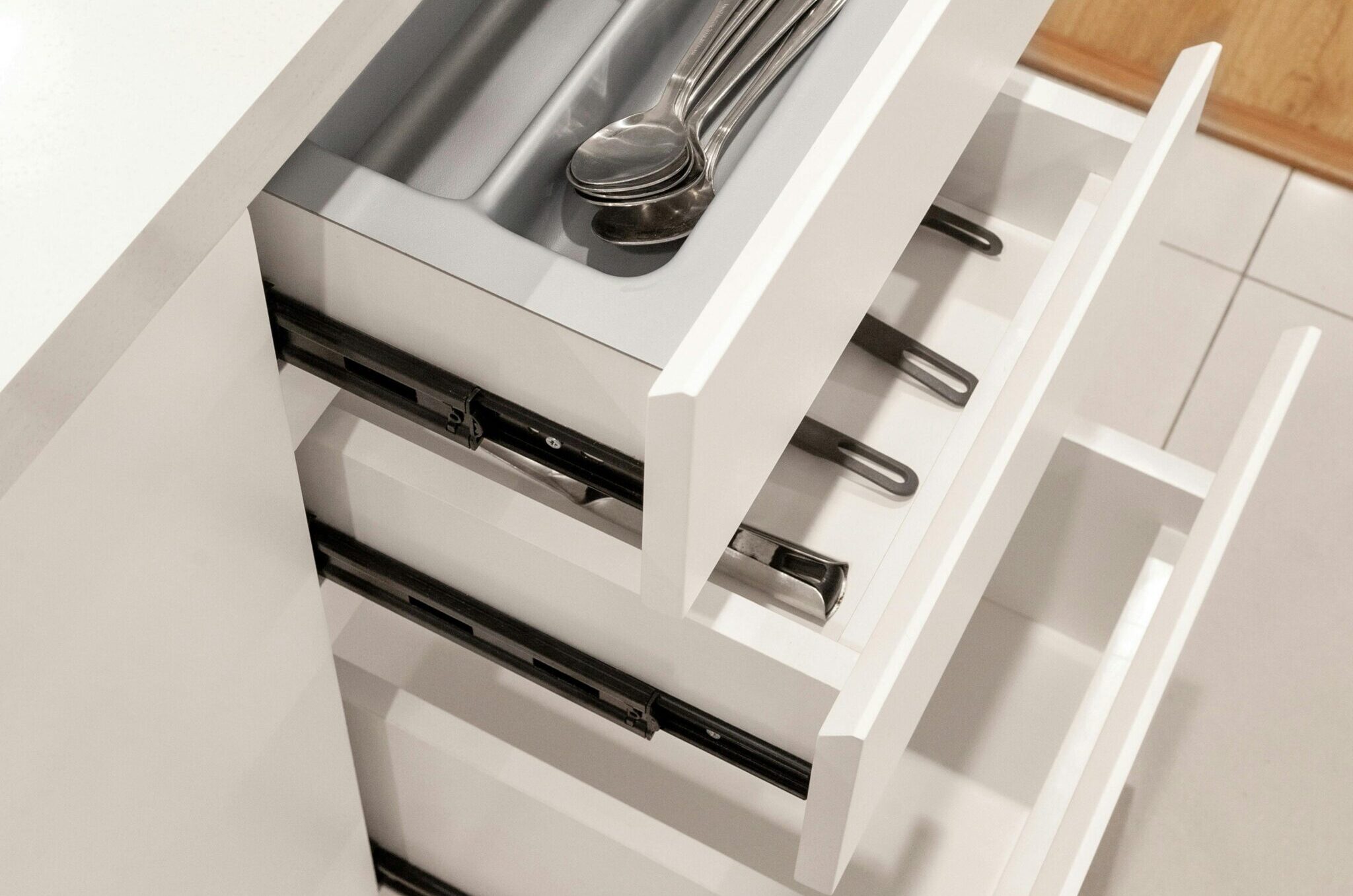 Top-down view of open kitchen drawers featuring a utensil organizer with spoons.
